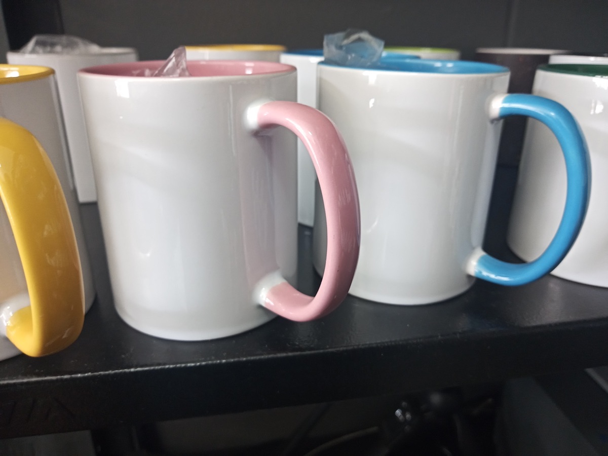 Canecas brancas com alças coloridas na prateleira